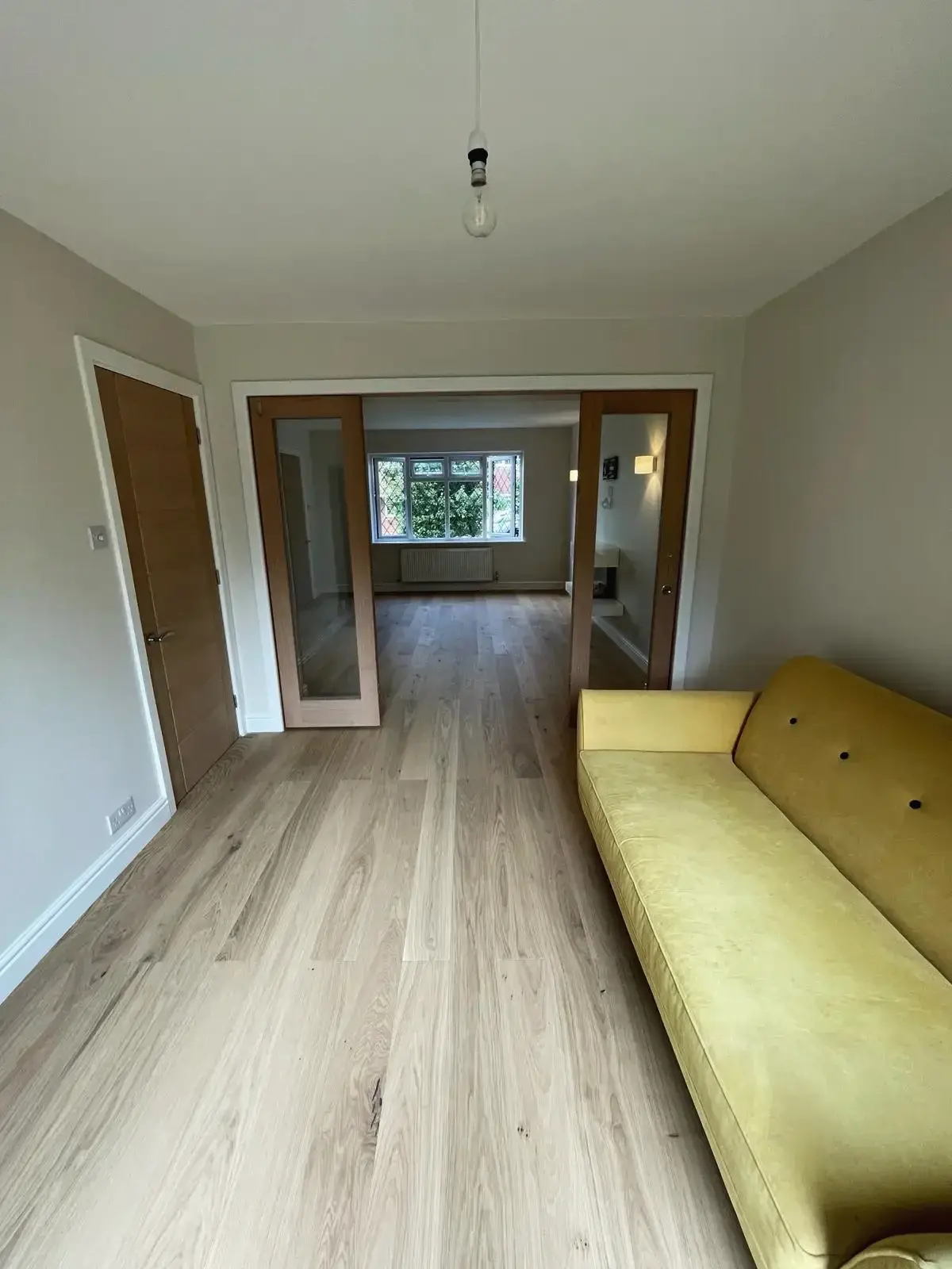 Long family room with an oak floor and glazed doors through to the rest of the house
