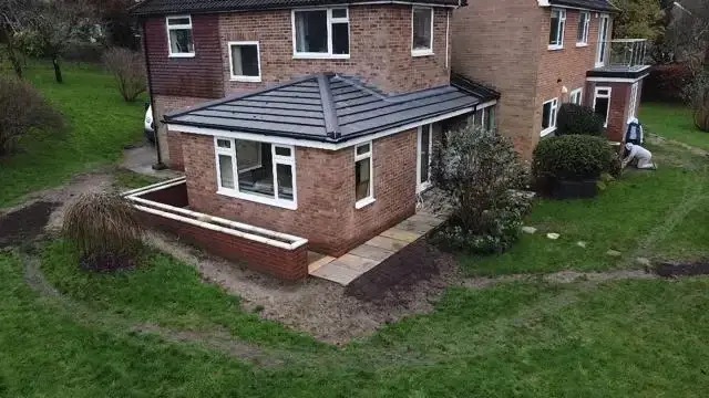 Aerial view of a single-storey brick extension with a tiled hipped roof, wrapped by a raised planter wall
