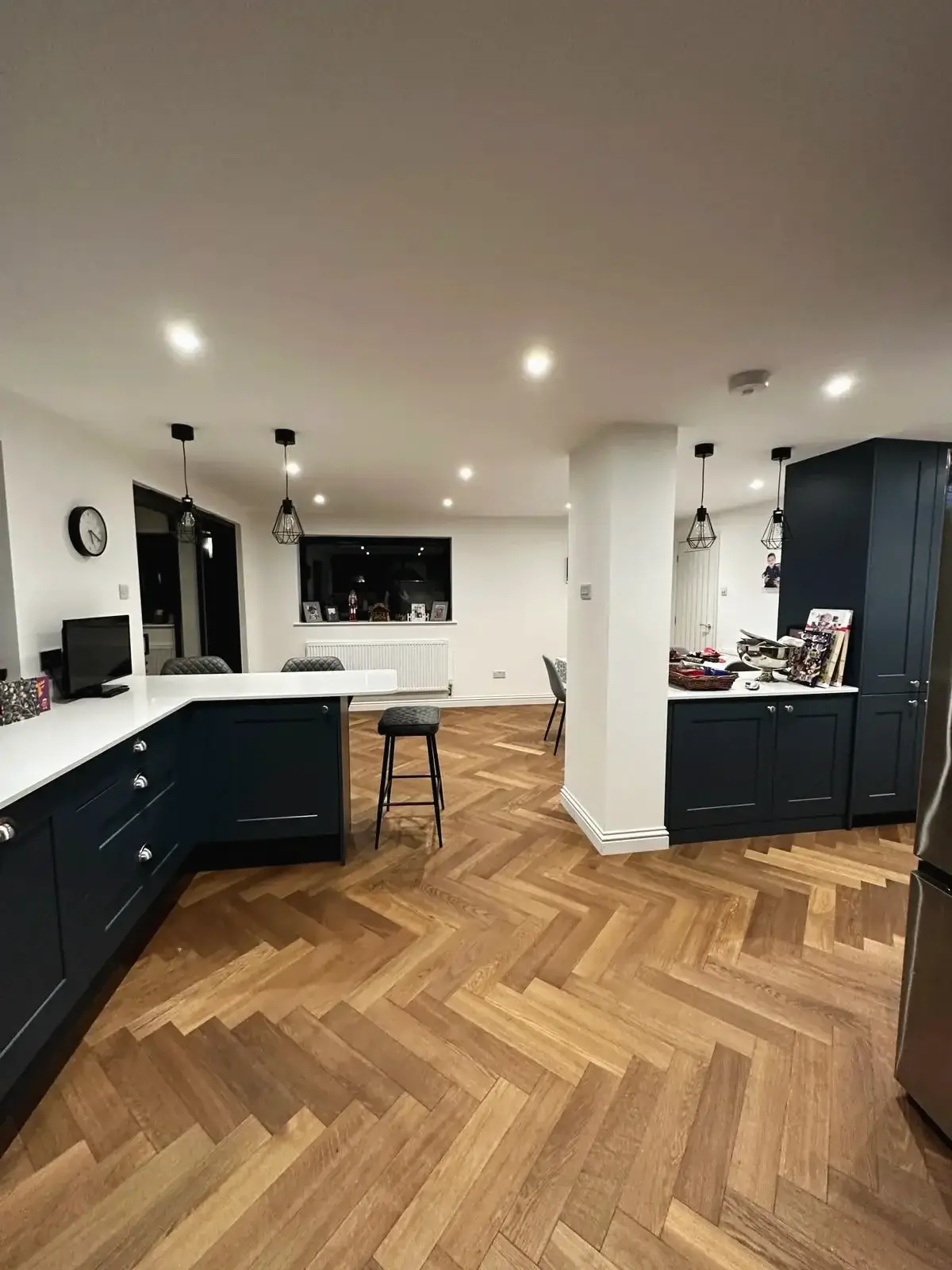 Kitchen diner extension with navy units, white worktops and a herringbone oak floor