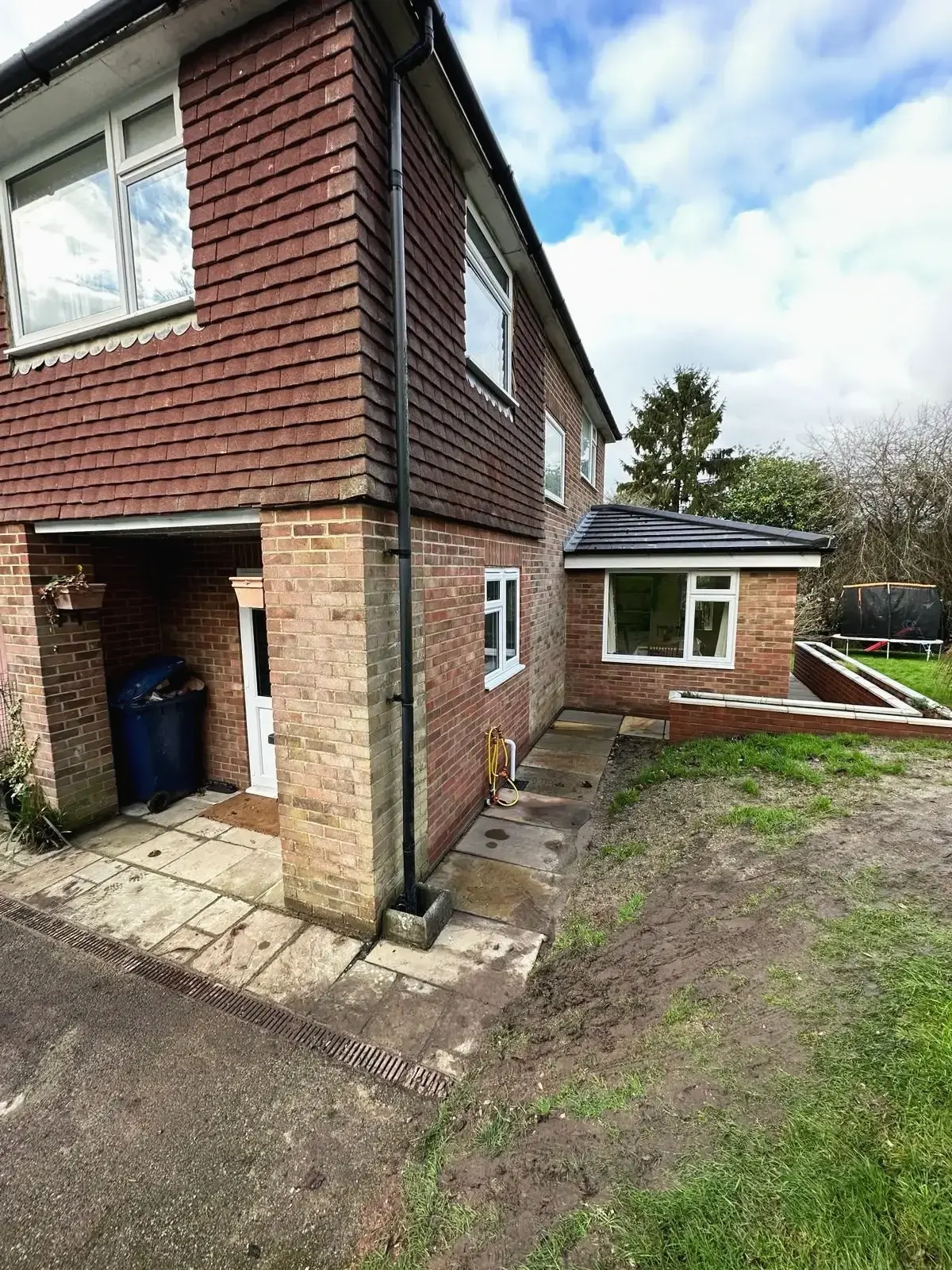 Side view of a house extension in new brickwork, with a single-storey section behind