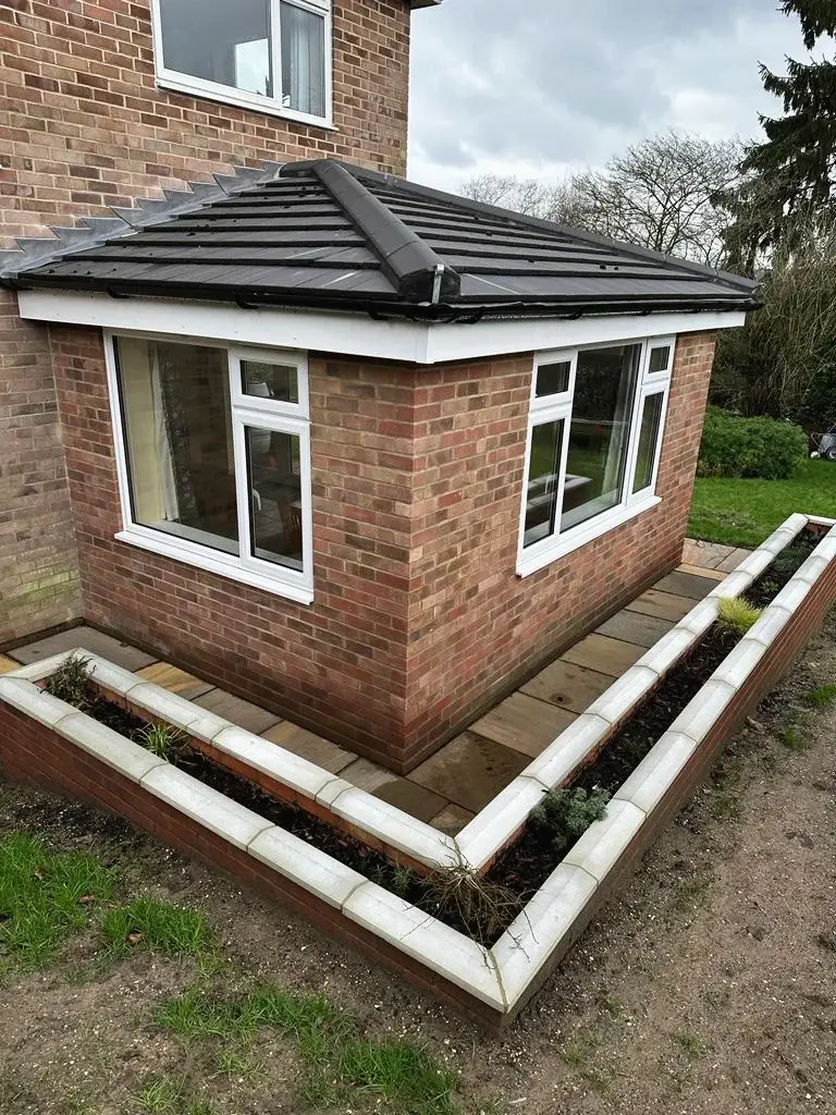 Single-storey brick extension with a tiled hipped roof and a new planter around it